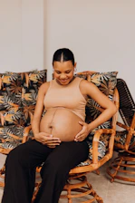 a pregnant woman sitting on a wicker chair
