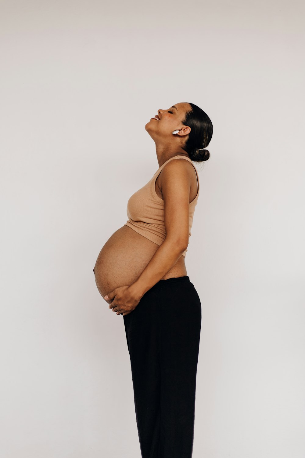 a pregnant woman in a tan top and black pants