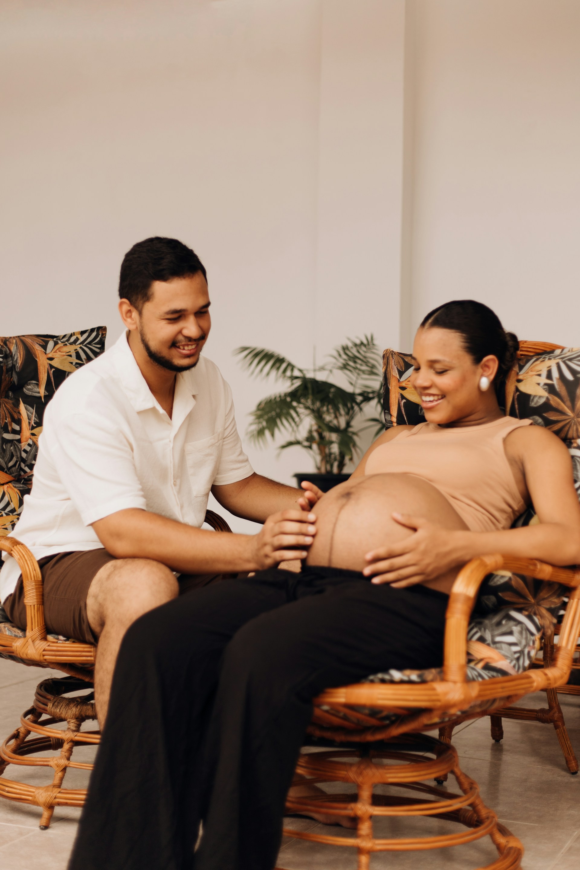 a pregnant woman sitting in a chair next to a man