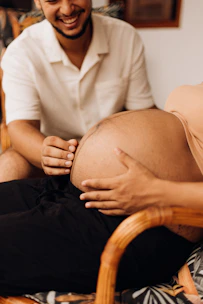 a man sitting in a chair with a pregnant woman