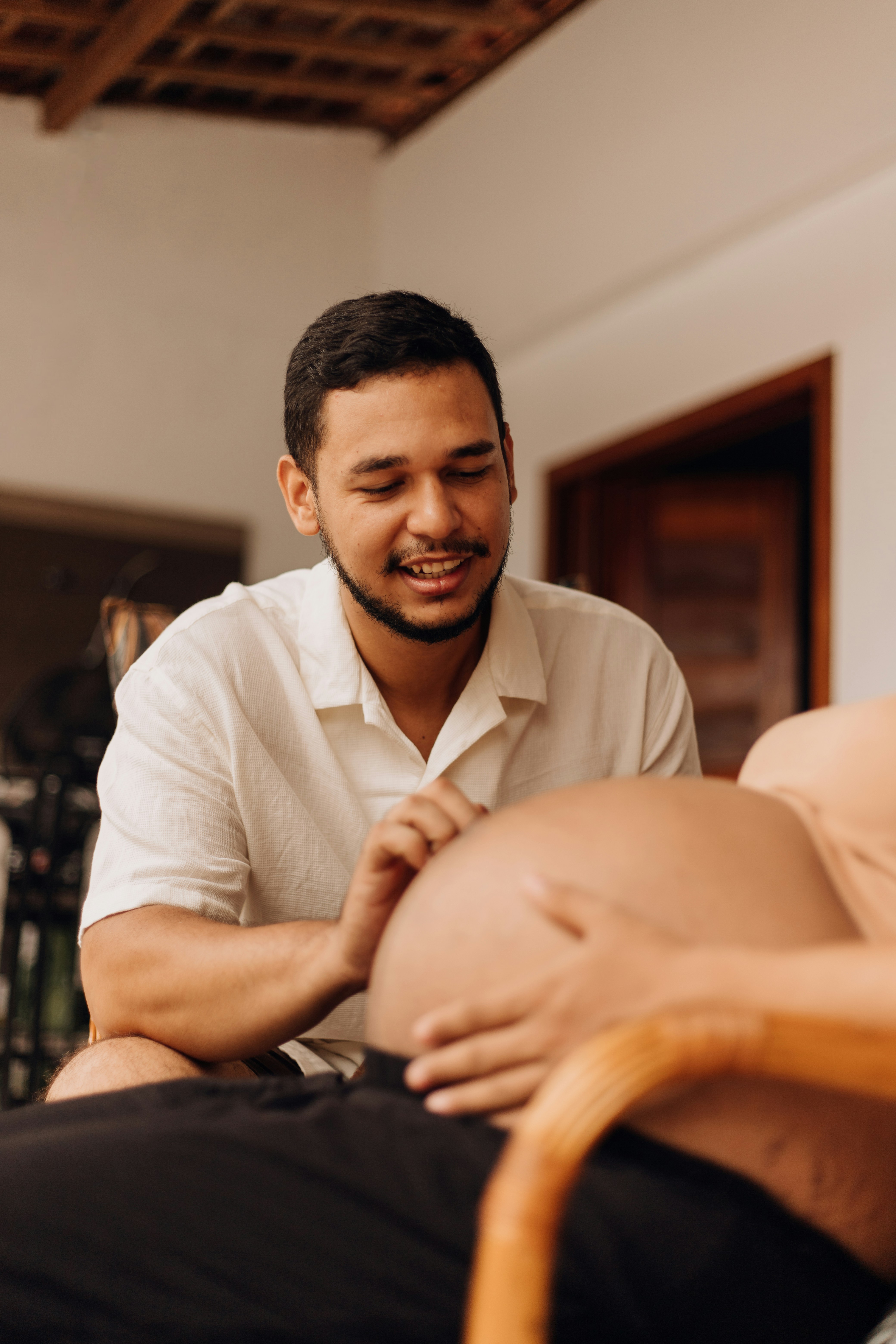 a man smiles as he holds his pregnant belly
