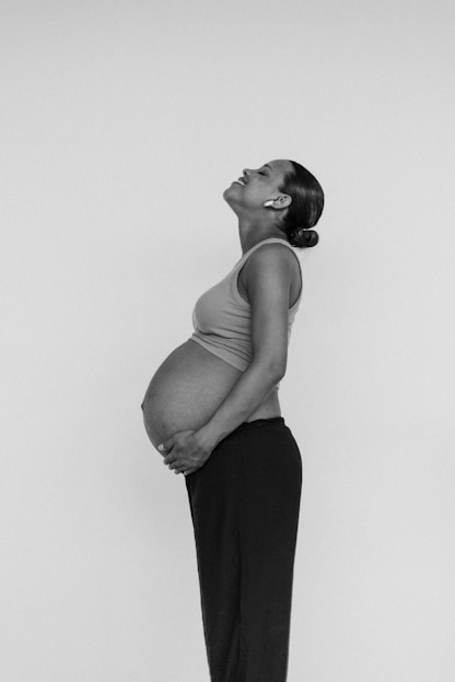 a pregnant woman standing in front of a white wall