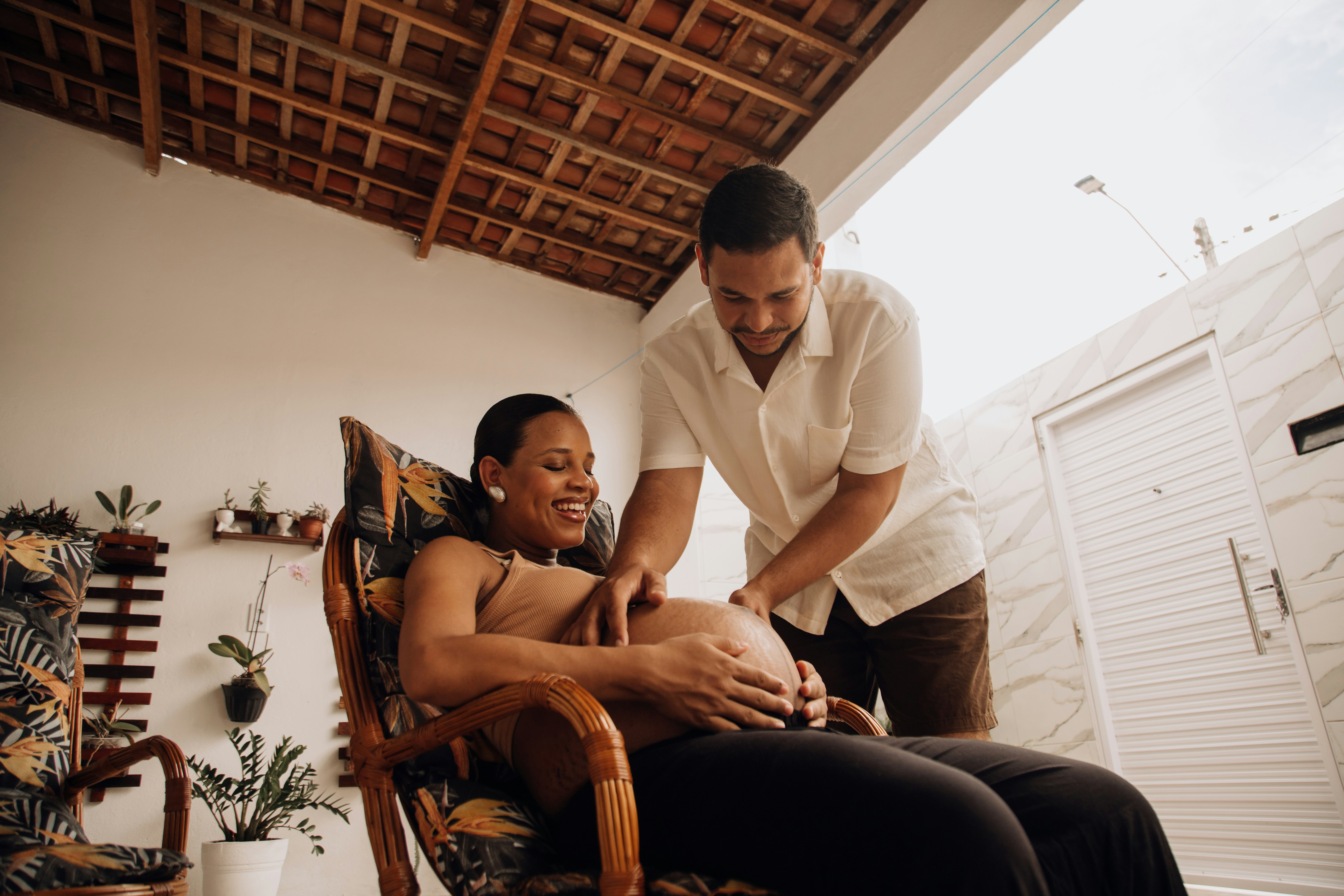 A pregnant woman lying on her side receiving a massage from a therapist in a peaceful and dimly lit spa room.