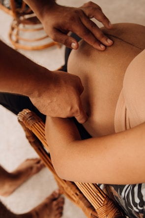 a woman sitting in a wicker chair touching her stomach
