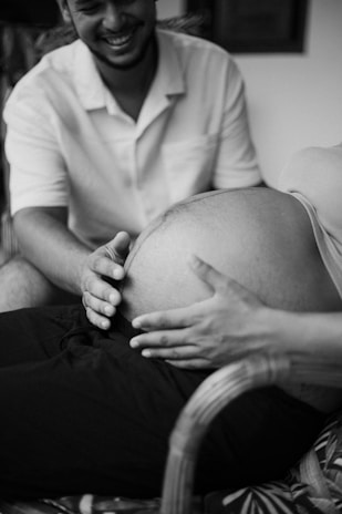 a black and white photo of a man holding his pregnant belly