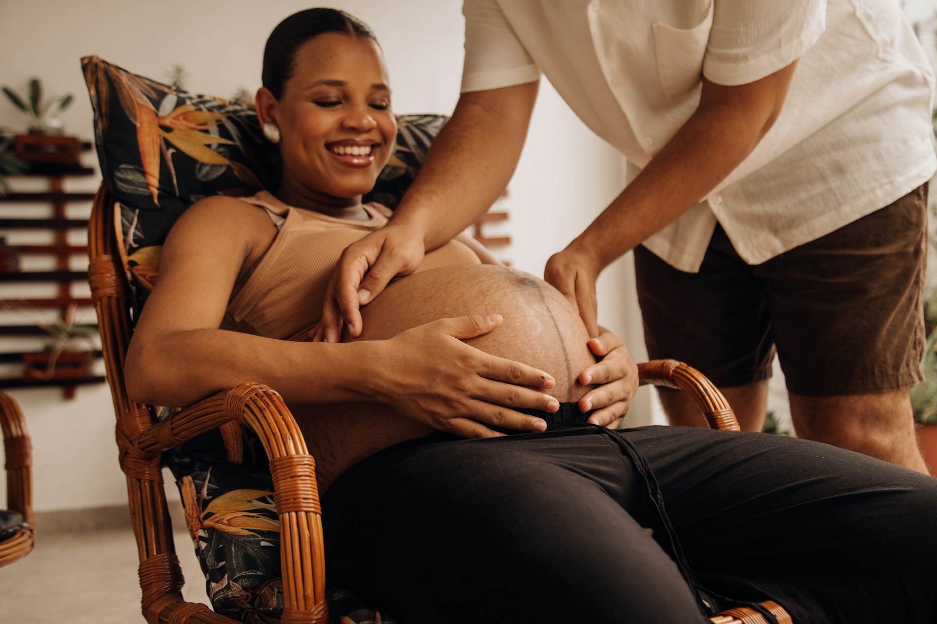 a pregnant woman sitting in a chair with a man standing behind her