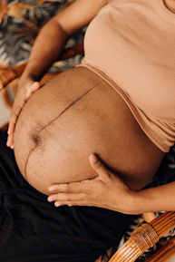 a pregnant woman sitting in a chair holding her belly