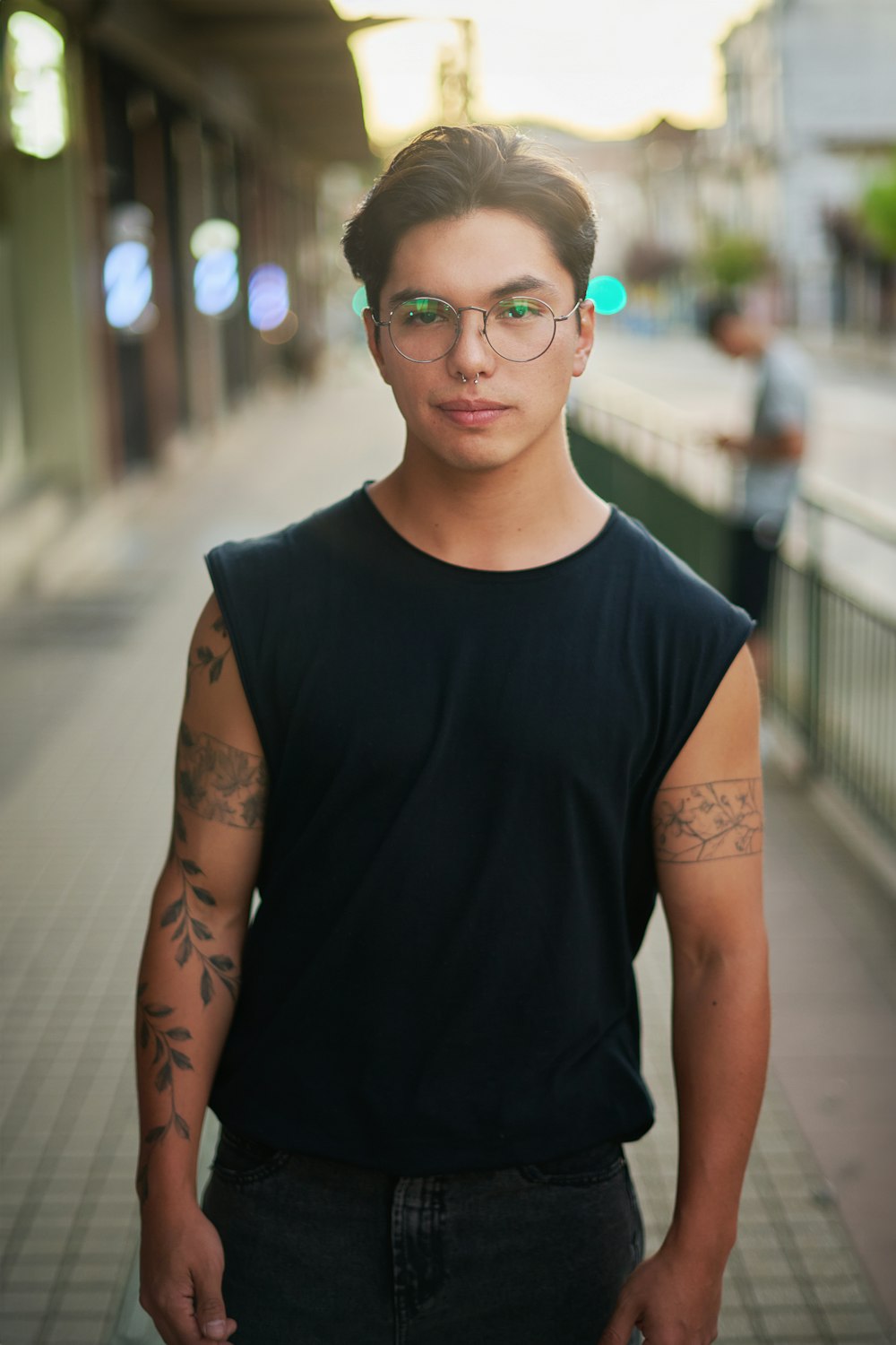 a man with glasses standing on a sidewalk