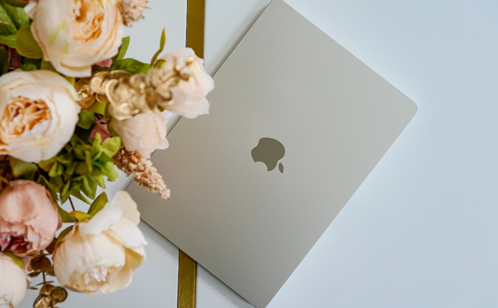 a bouquet of flowers next to an apple laptop