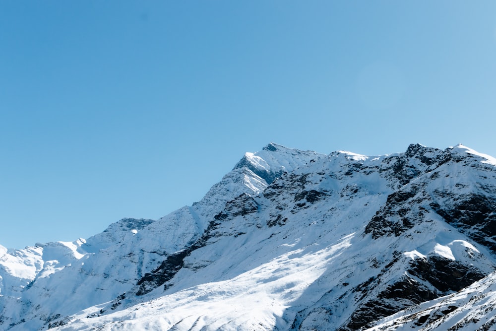 a large mountain covered in snow under a blue sky