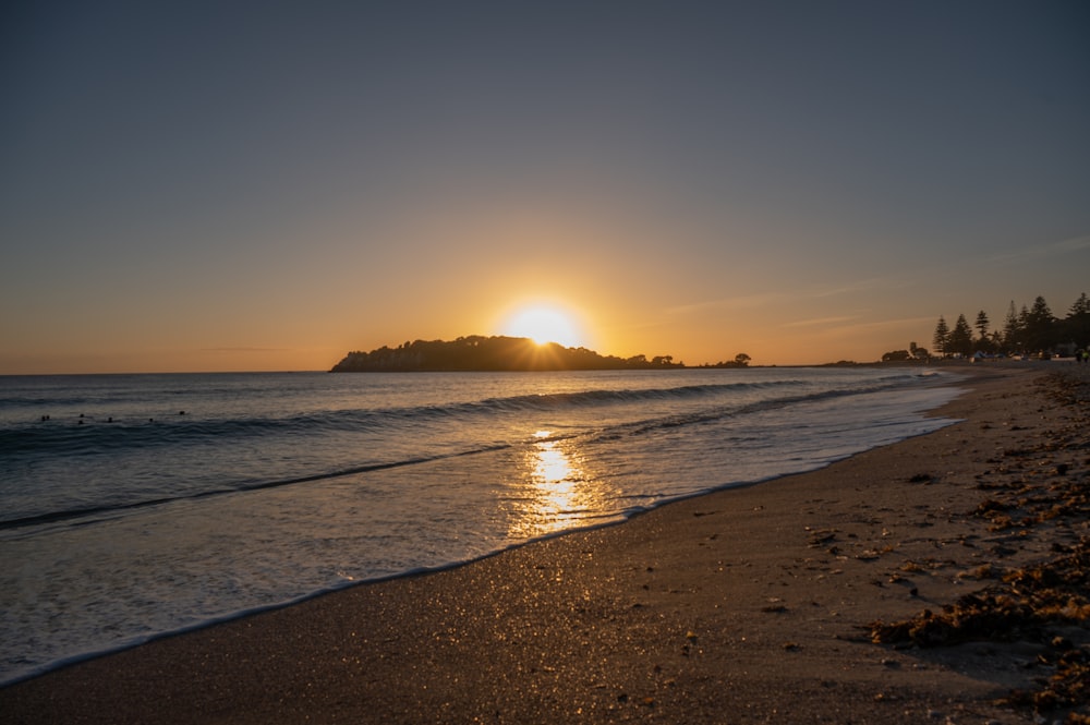 Il sole sta tramontando sull'oceano con una piccola isola in lontananza