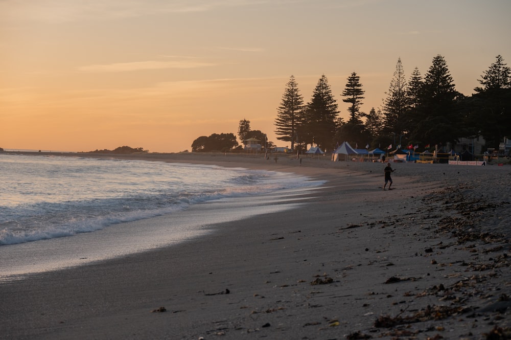 a person walking on the beach at sunset