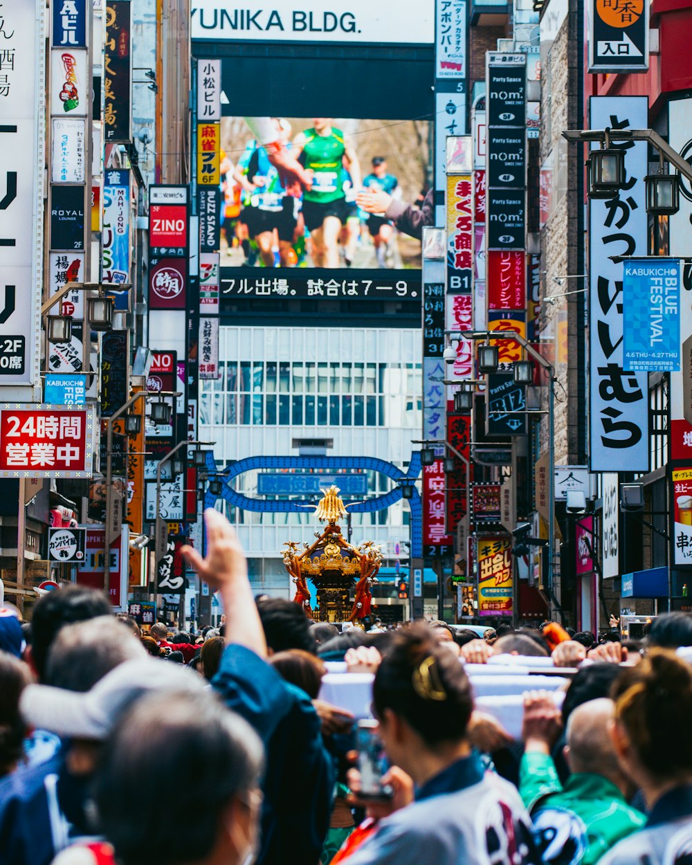 a crowd of people walking down a street next to tall buildings