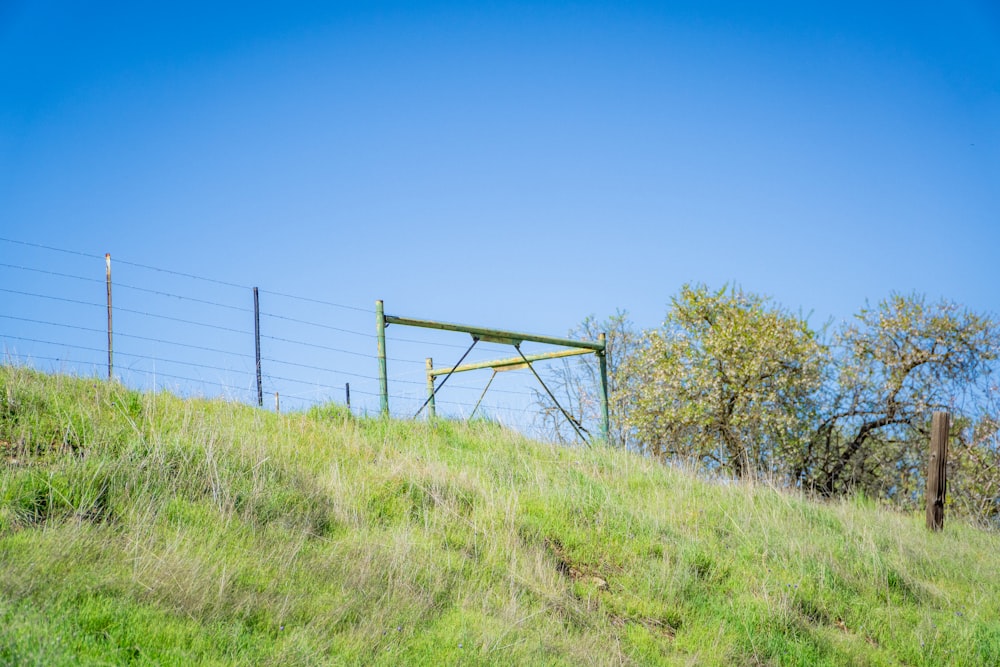 a grassy hill with a gate on top of it
