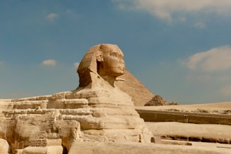 a large sphinx statue in front of a large pyramid