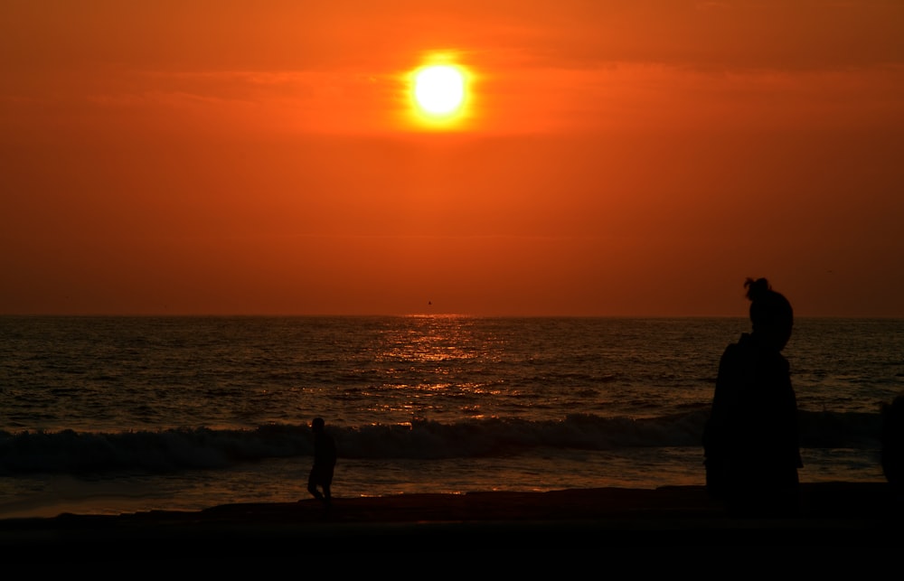 a couple of people standing on top of a beach near the ocean