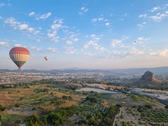 two hot air balloons flying over a city