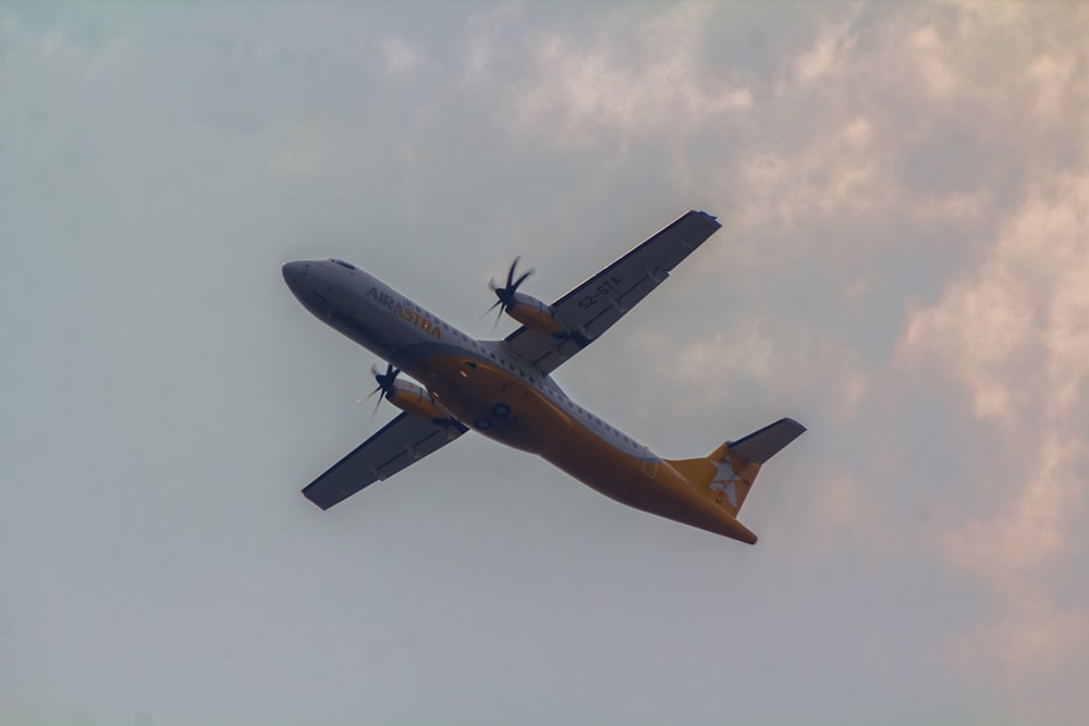 a large airplane flying through a cloudy sky