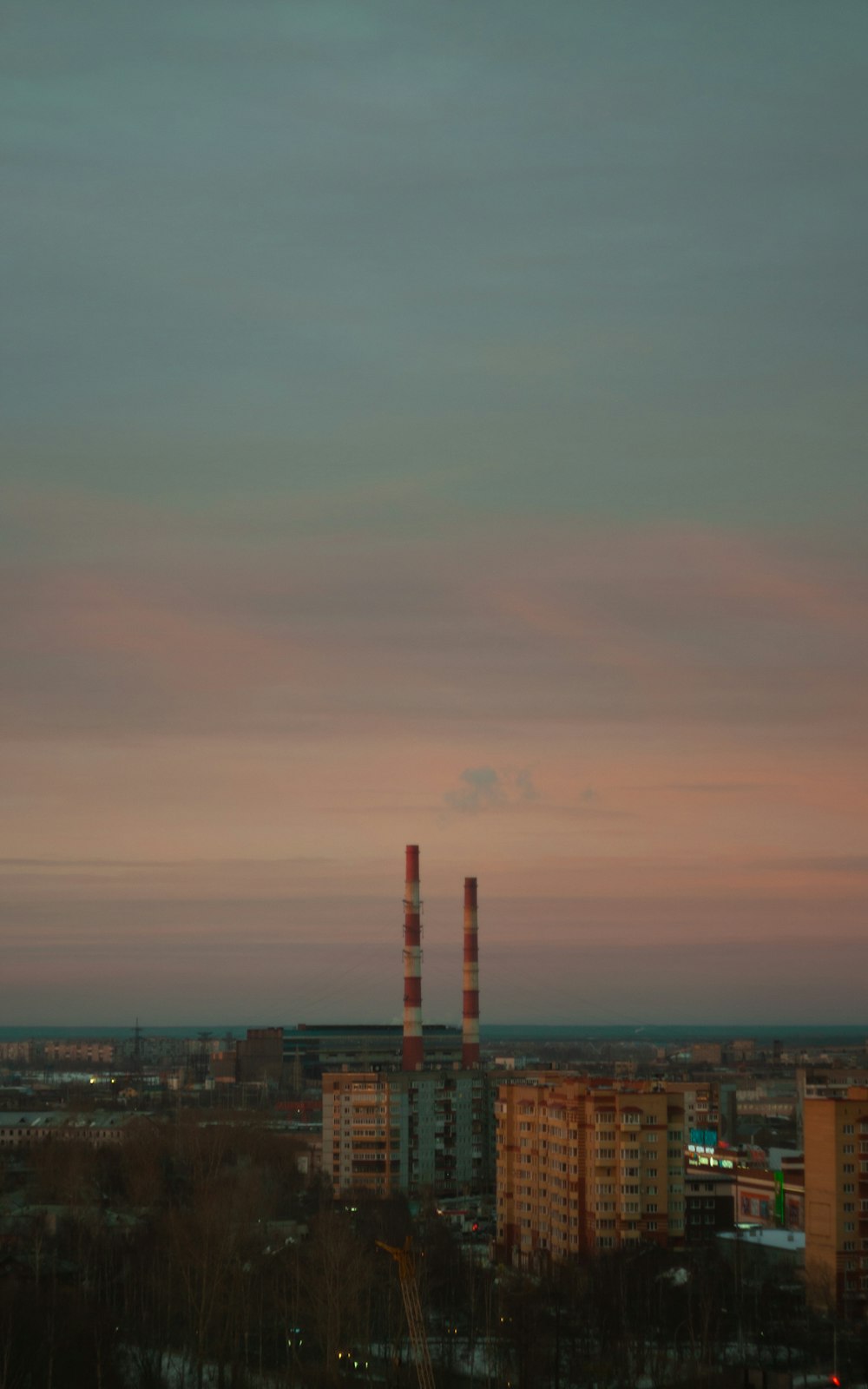 a view of a city at sunset with smoke stacks in the distance