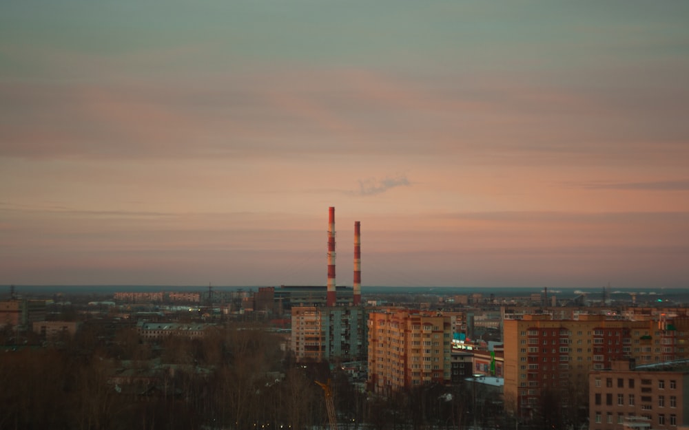 uma vista de uma cidade ao pôr do sol com chaminés de fumaça