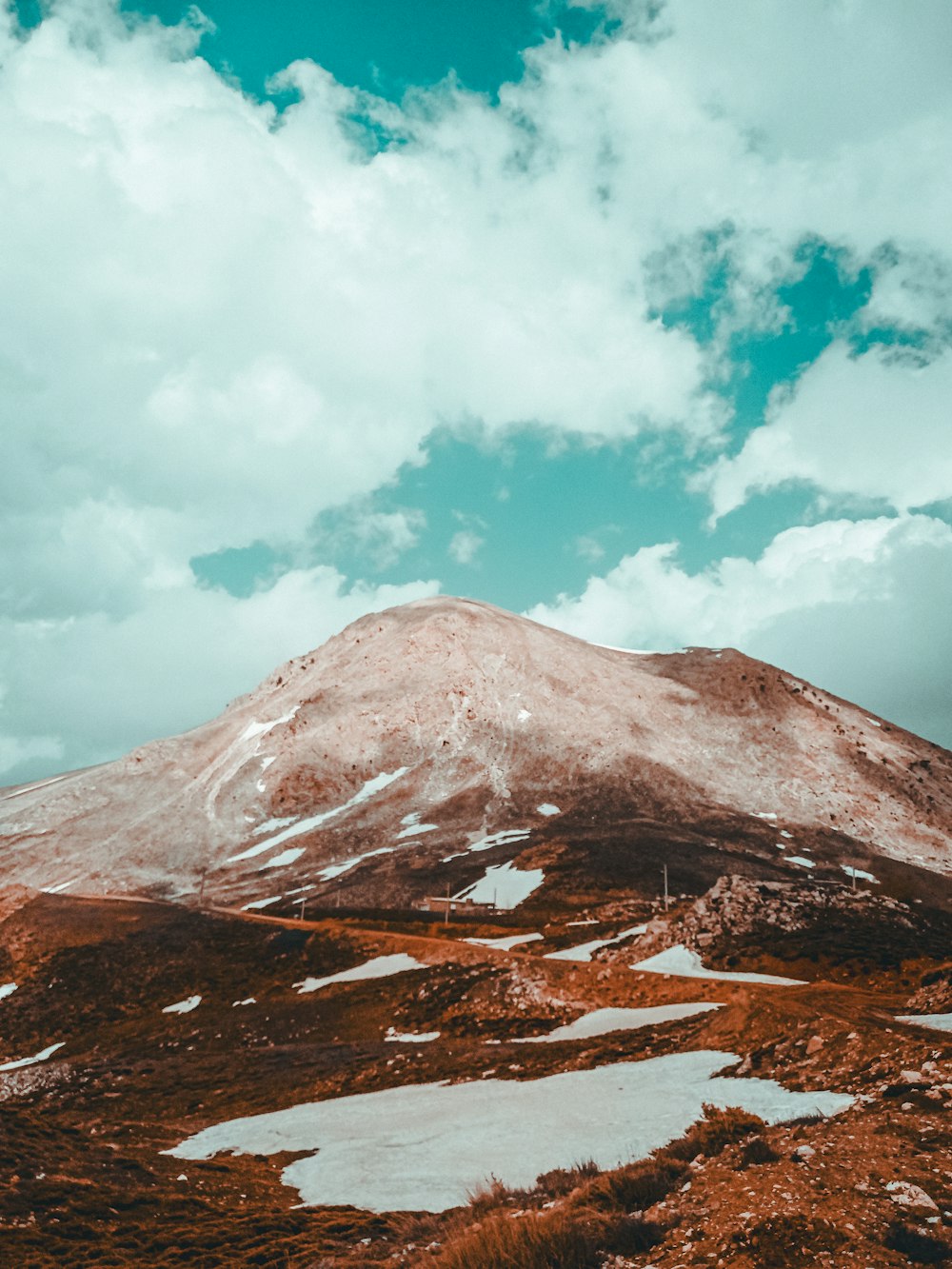 a snow covered mountain under a cloudy blue sky