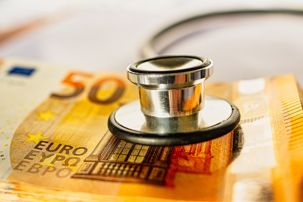 A stethoscope placed on top of a pile of money symbolizing rising healthcare costs