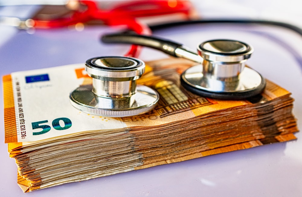 a pile of money with a stethoscope on top of it