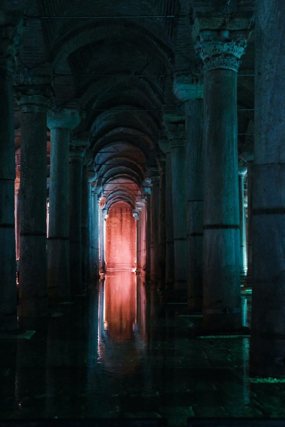 a long hallway with columns and a light at the end