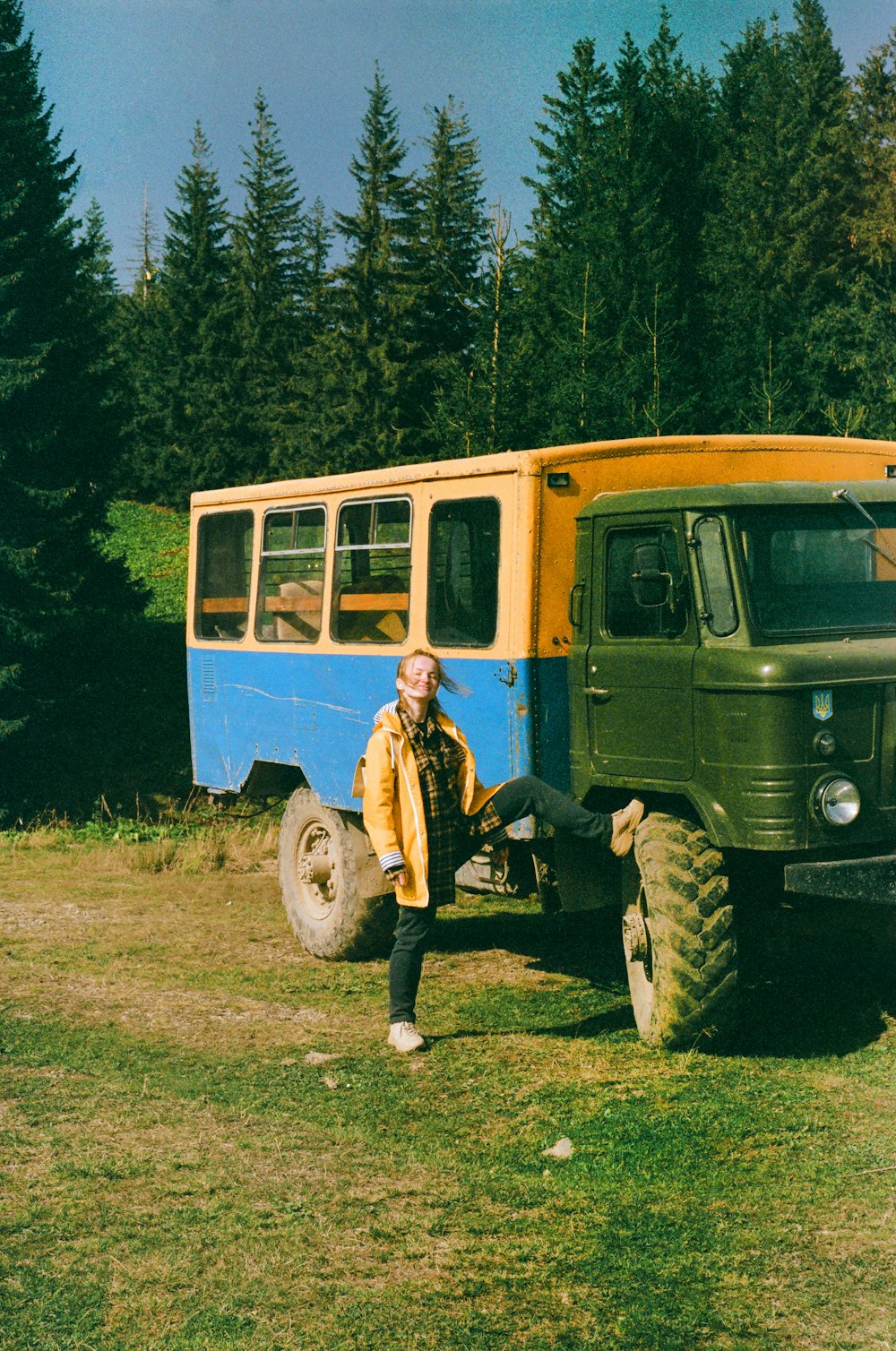 a man standing in front of a green and yellow bus