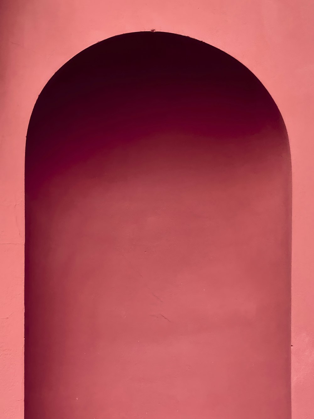 a person sitting on a bench in front of a pink wall