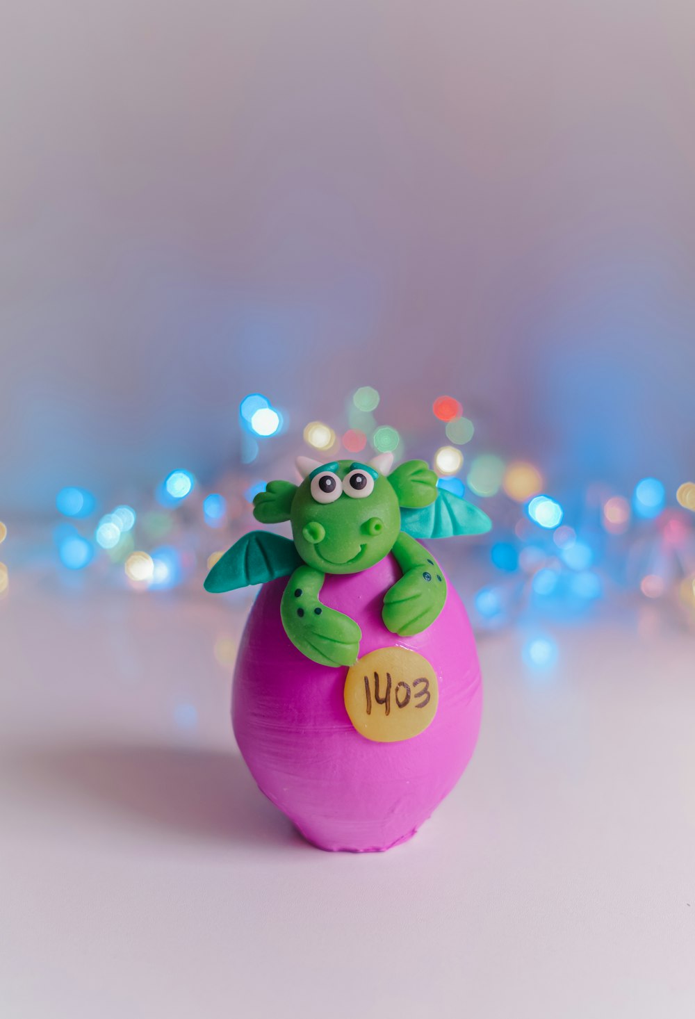 a green dragon sitting on top of a pink ball