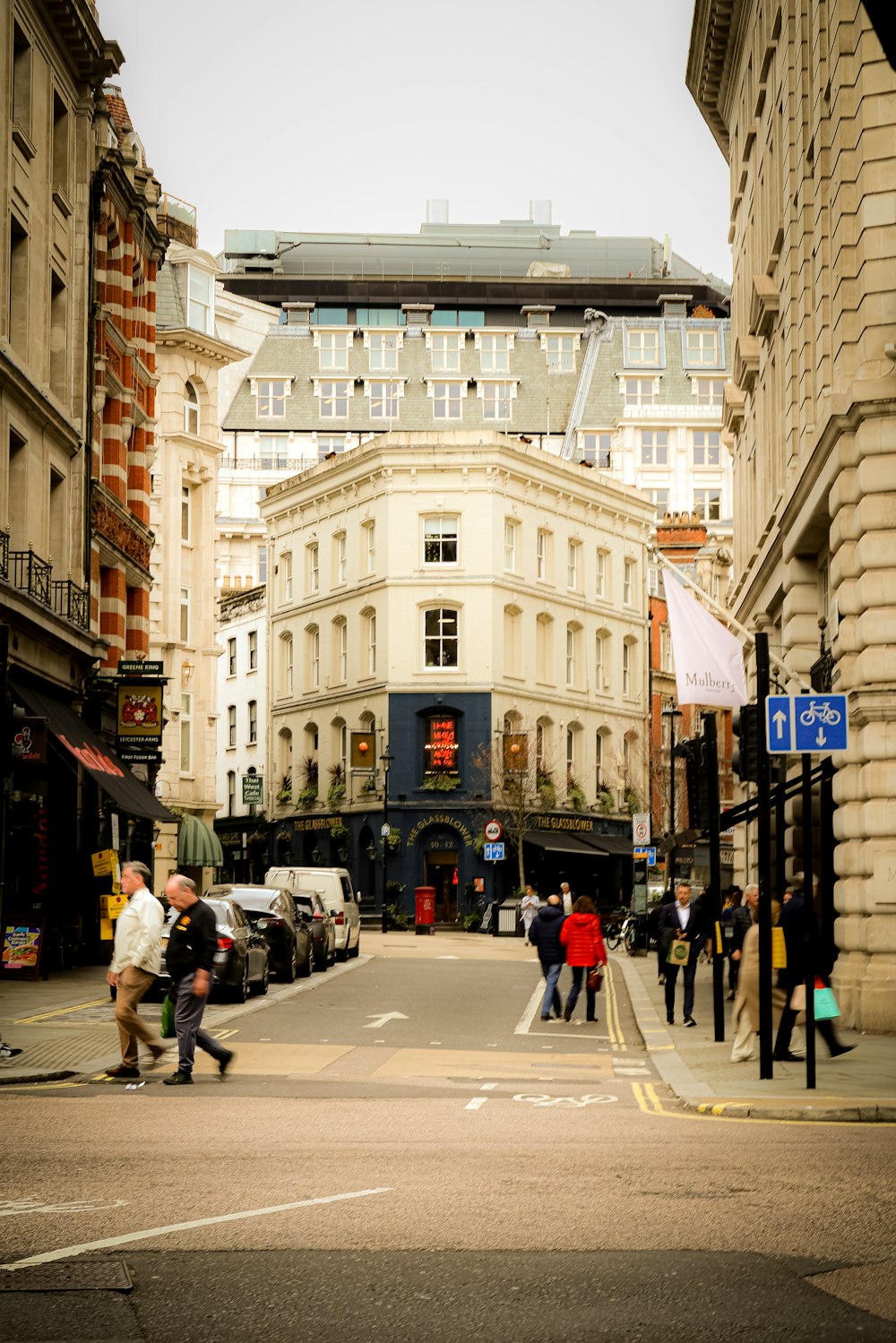 a group of people walking down a street next to tall buildings