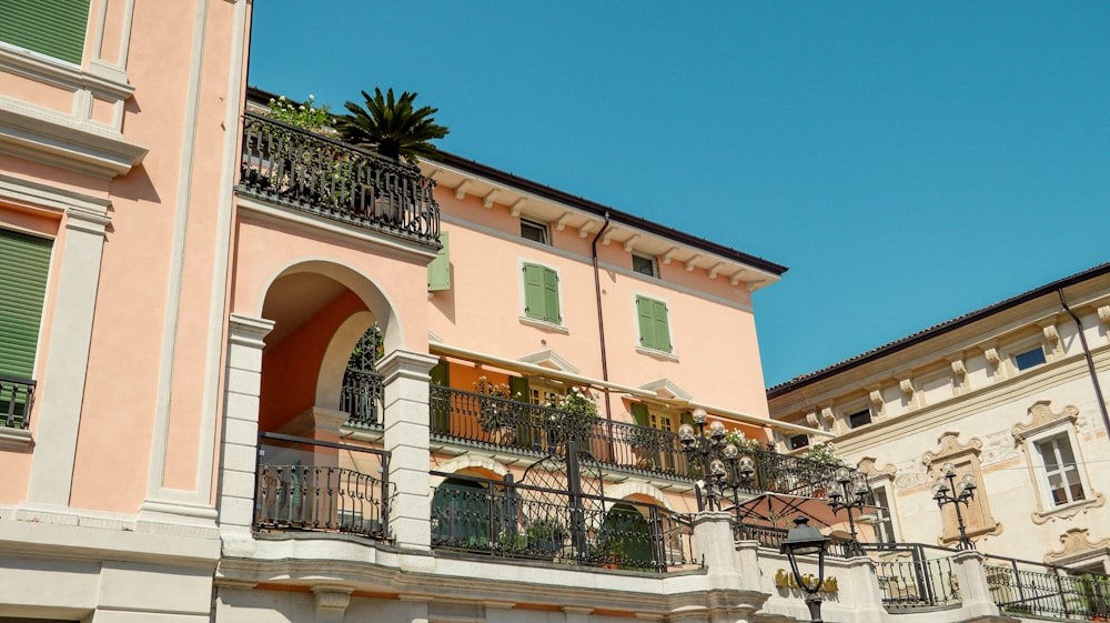 a pink building with green shutters and balconies