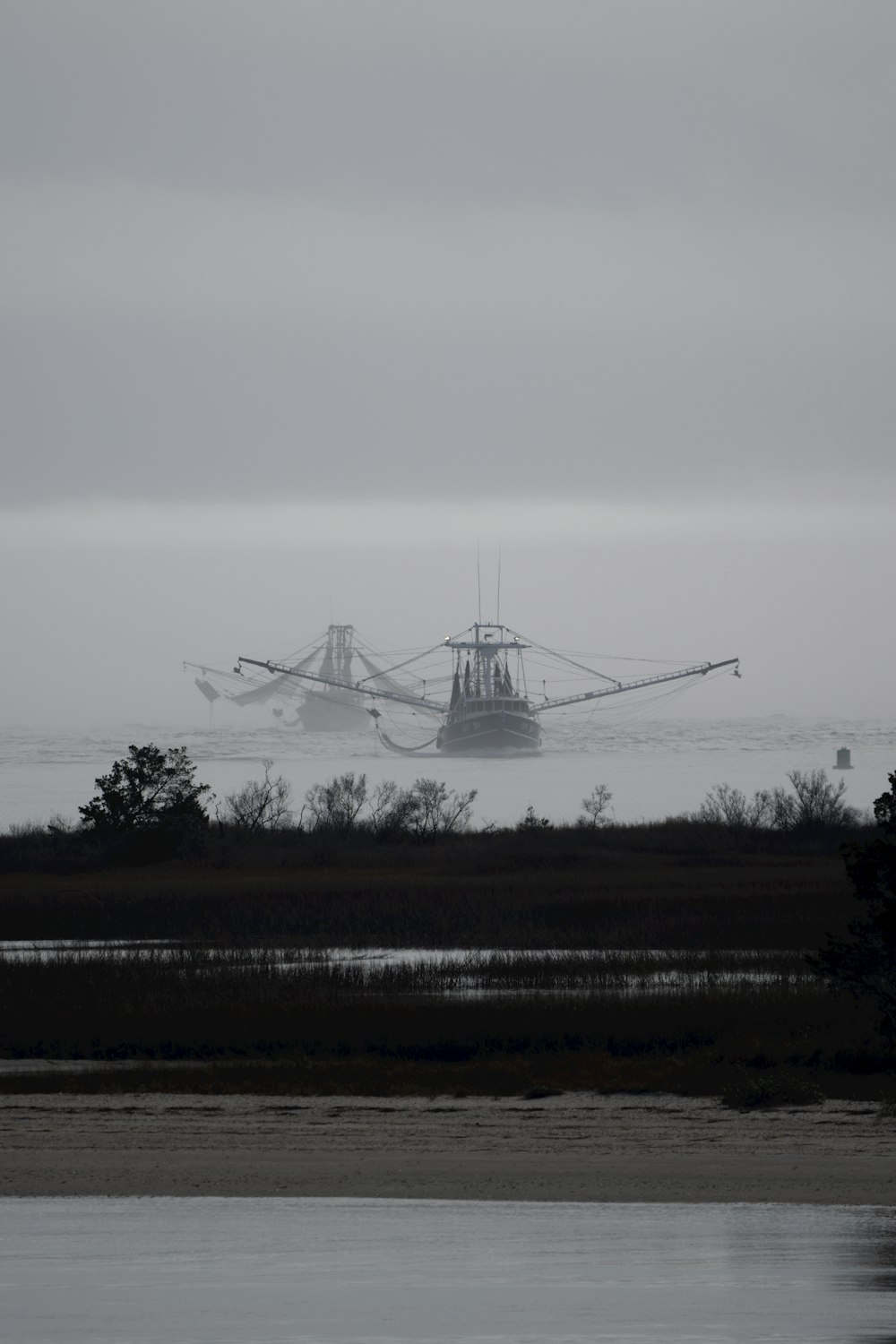 a fishing boat in the water on a foggy day