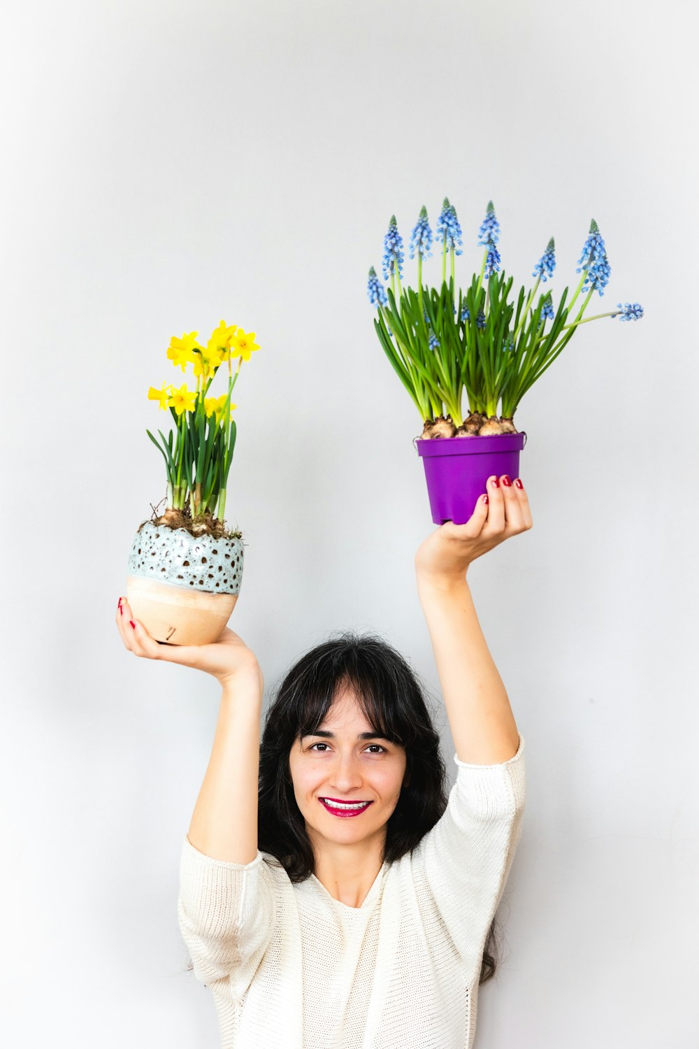 a woman holding two potted plants in front of her head