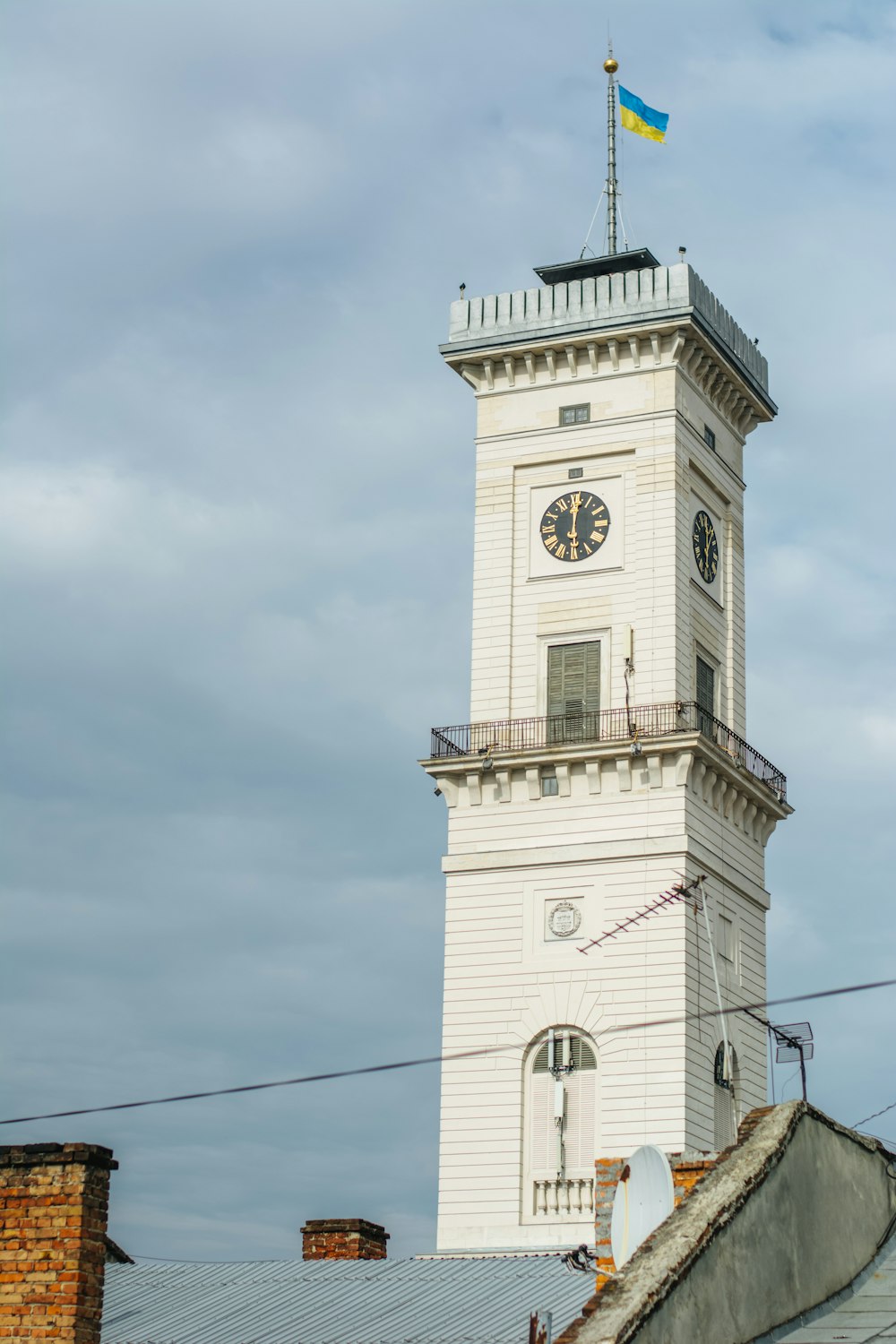 a tall white clock tower with a flag on top