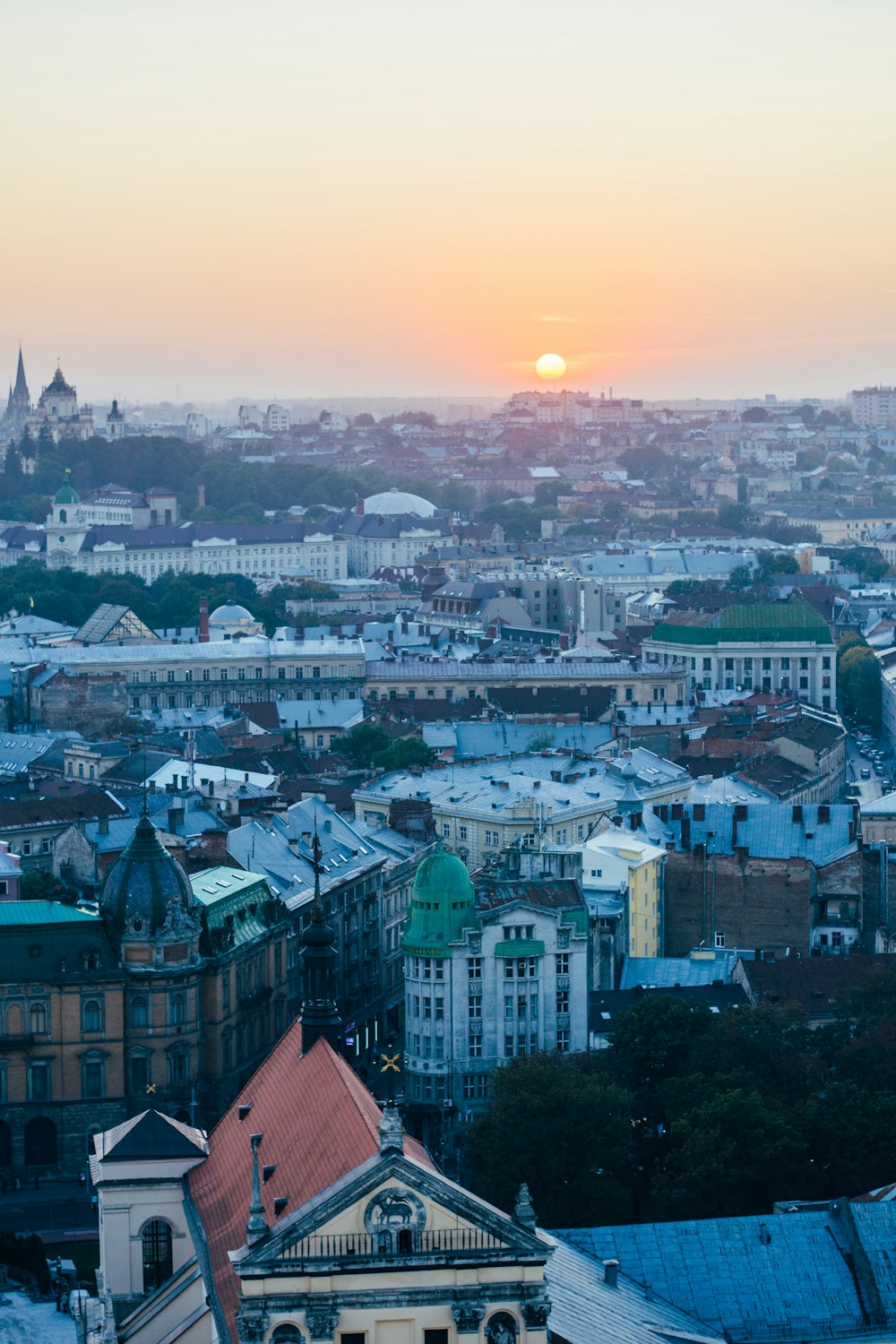 the sun is setting over a city with tall buildings