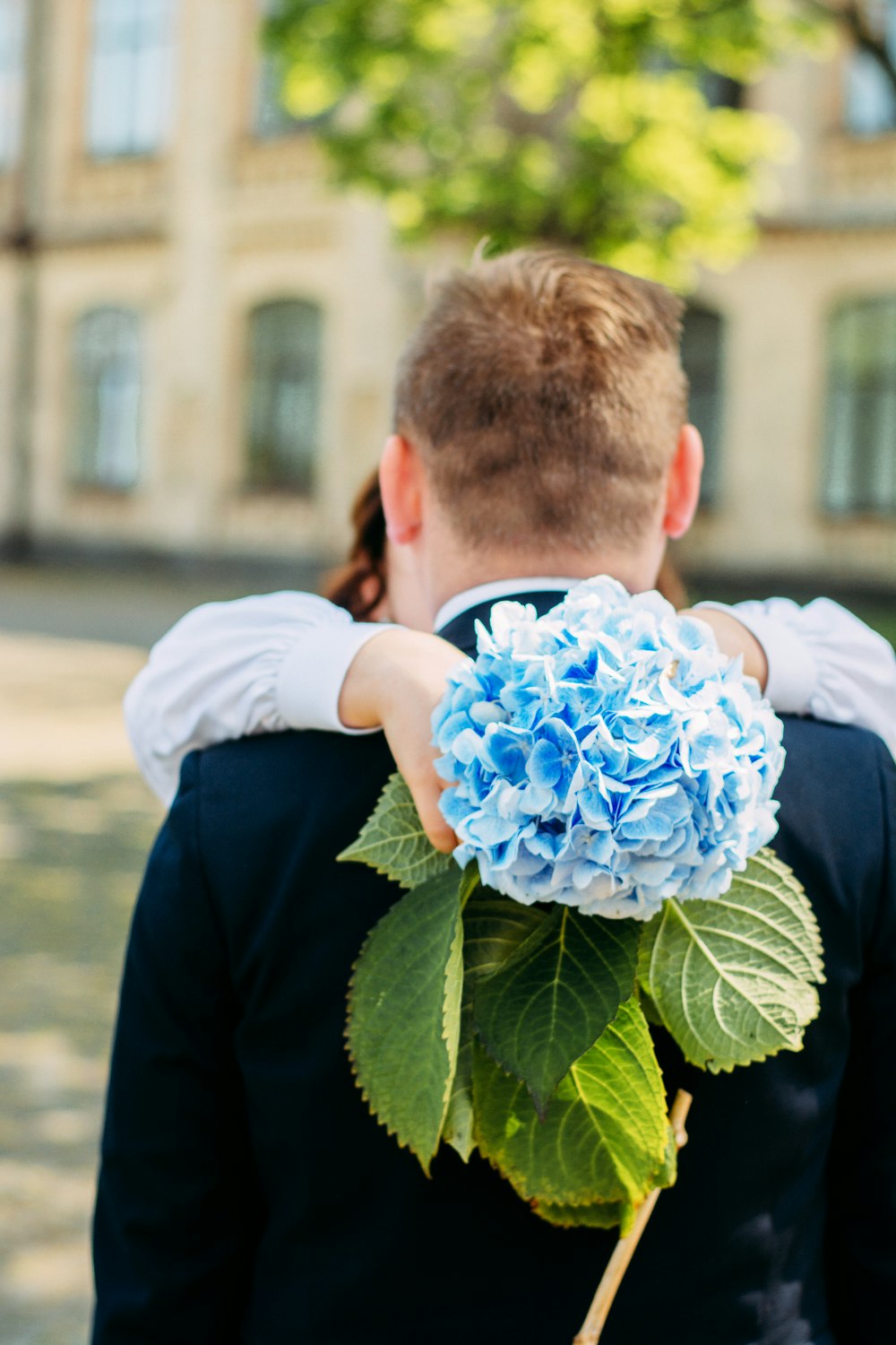 a young boy holding a blue flower in his hands