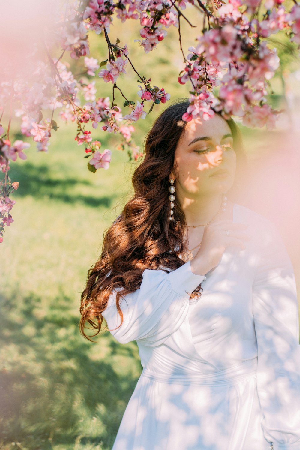 a woman in a white dress standing under a tree