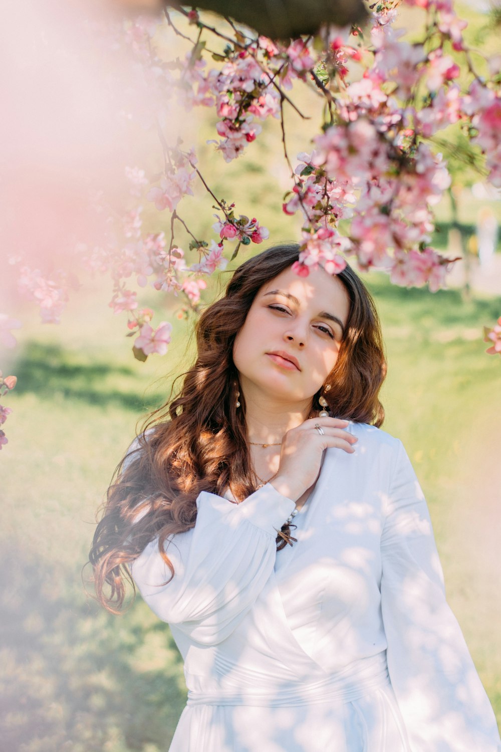 a woman standing under a tree with pink flowers