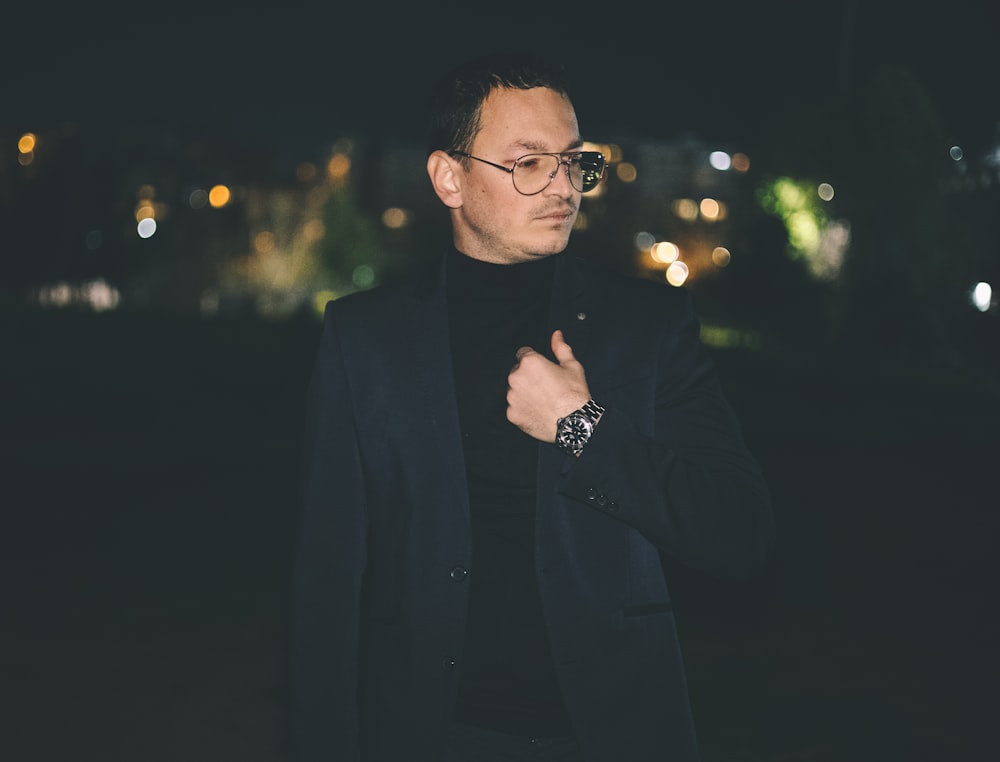 a man in a suit and glasses standing in the dark