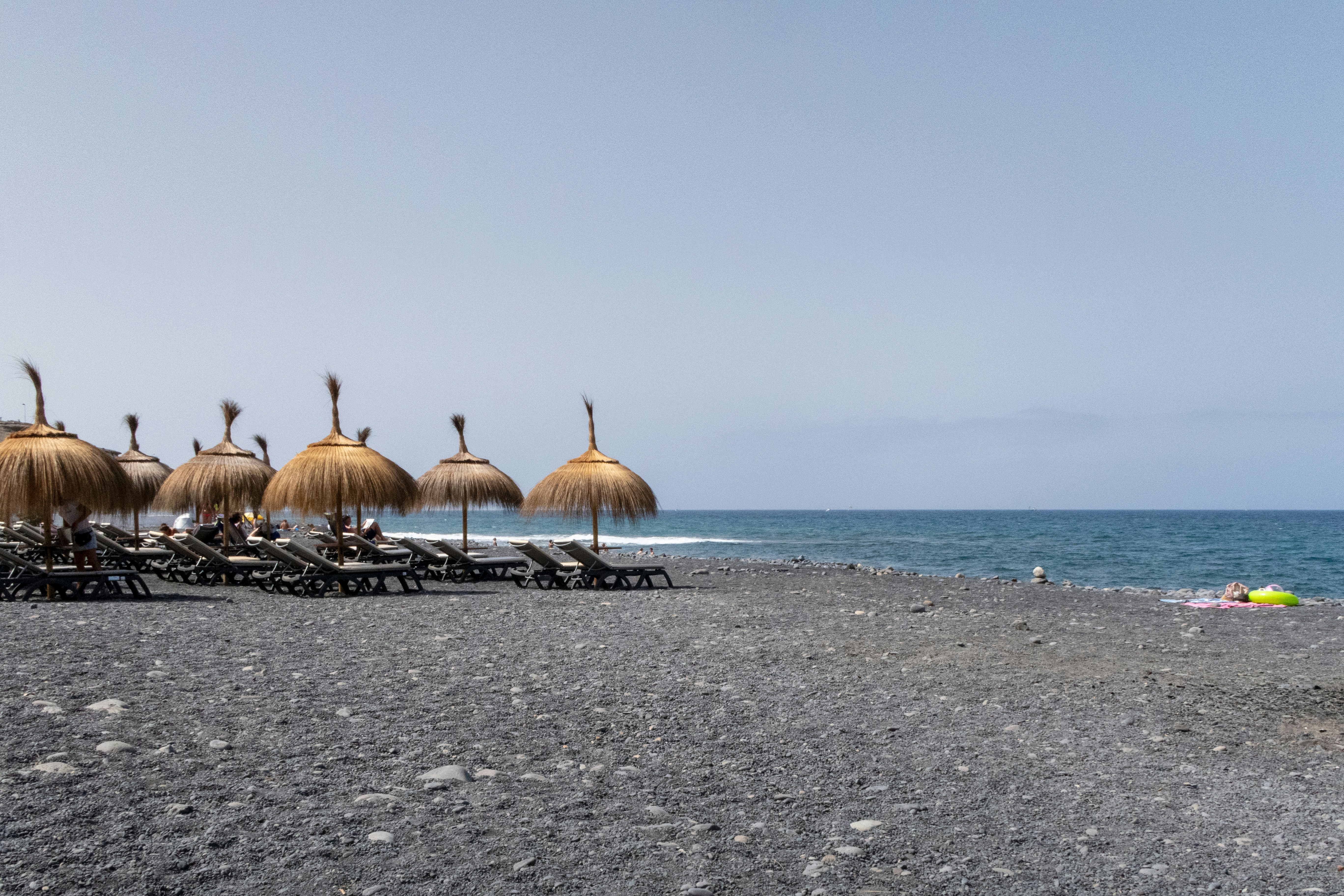 una playa con sillas y sombrillas en la arena