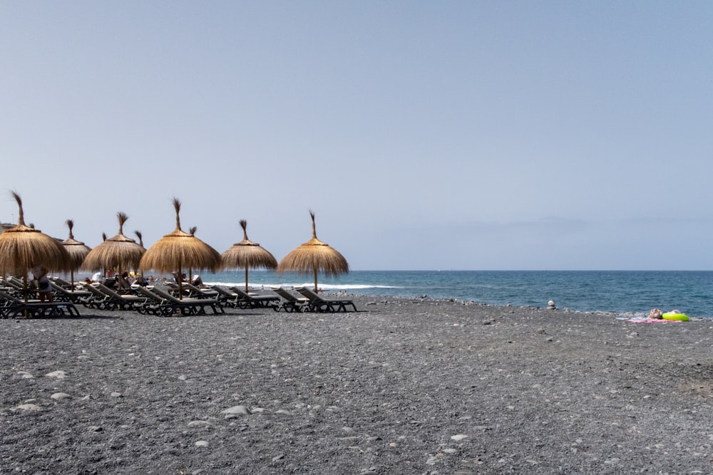 a beach with chairs and umbrellas on the sand