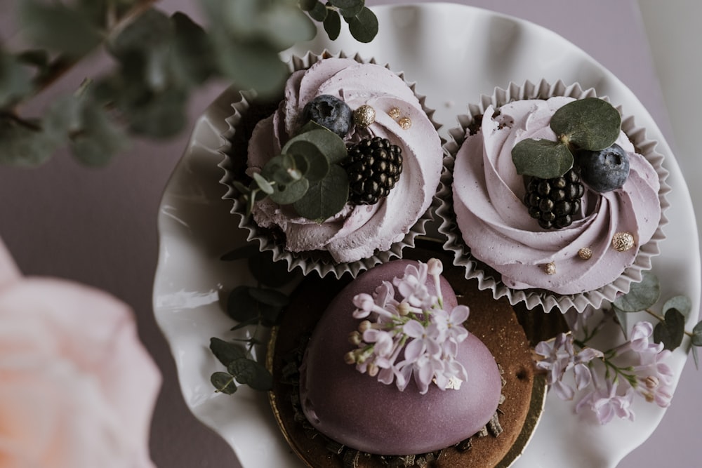 a white plate topped with cupcakes covered in frosting