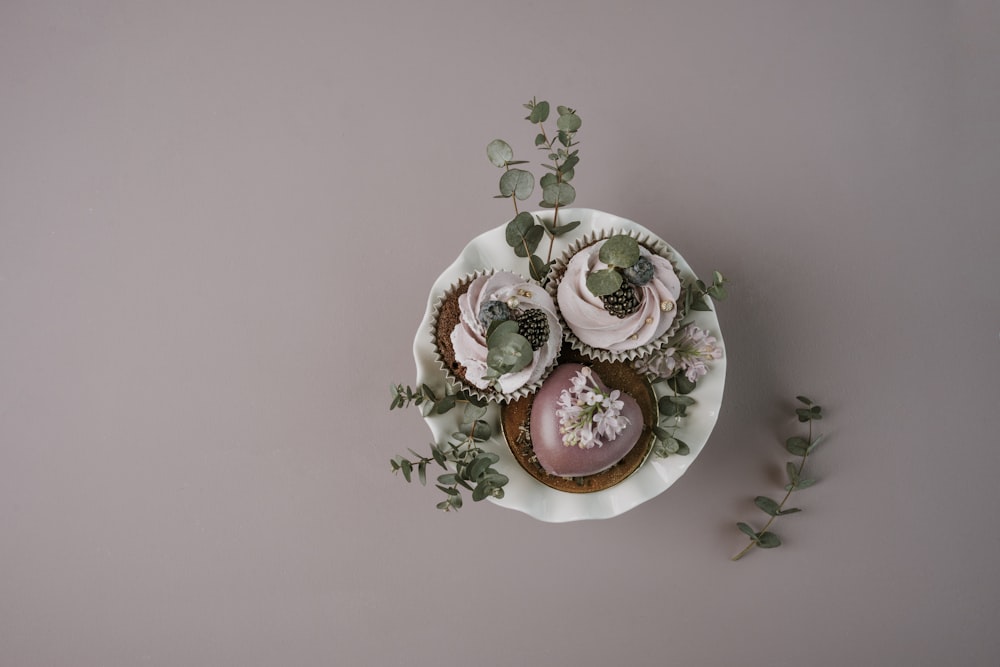 un plato de cupcakes con glaseado rosa y vegetación