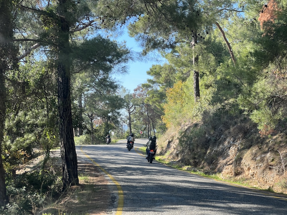 a couple of people riding motorcycles down a road