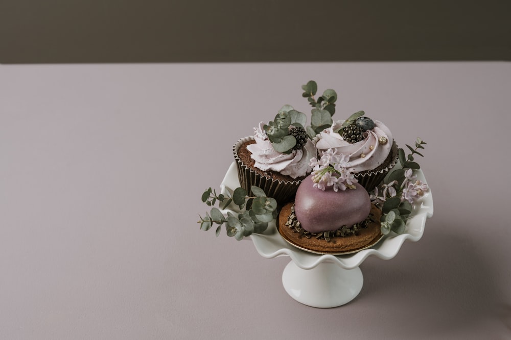 케이크 스탠드에 설탕 프로스팅과 꽃을 곁들인 두 개의 컵 케이크