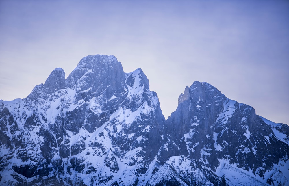 a mountain range covered in snow under a cloudy sky