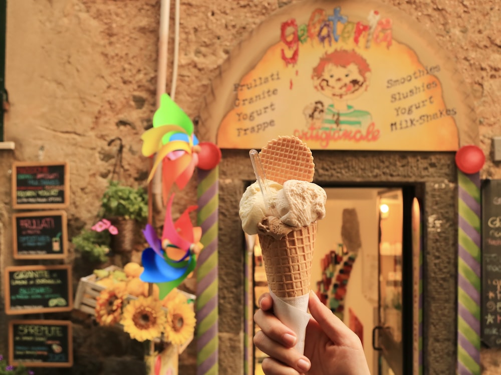 a person holding an ice cream cone in front of a building