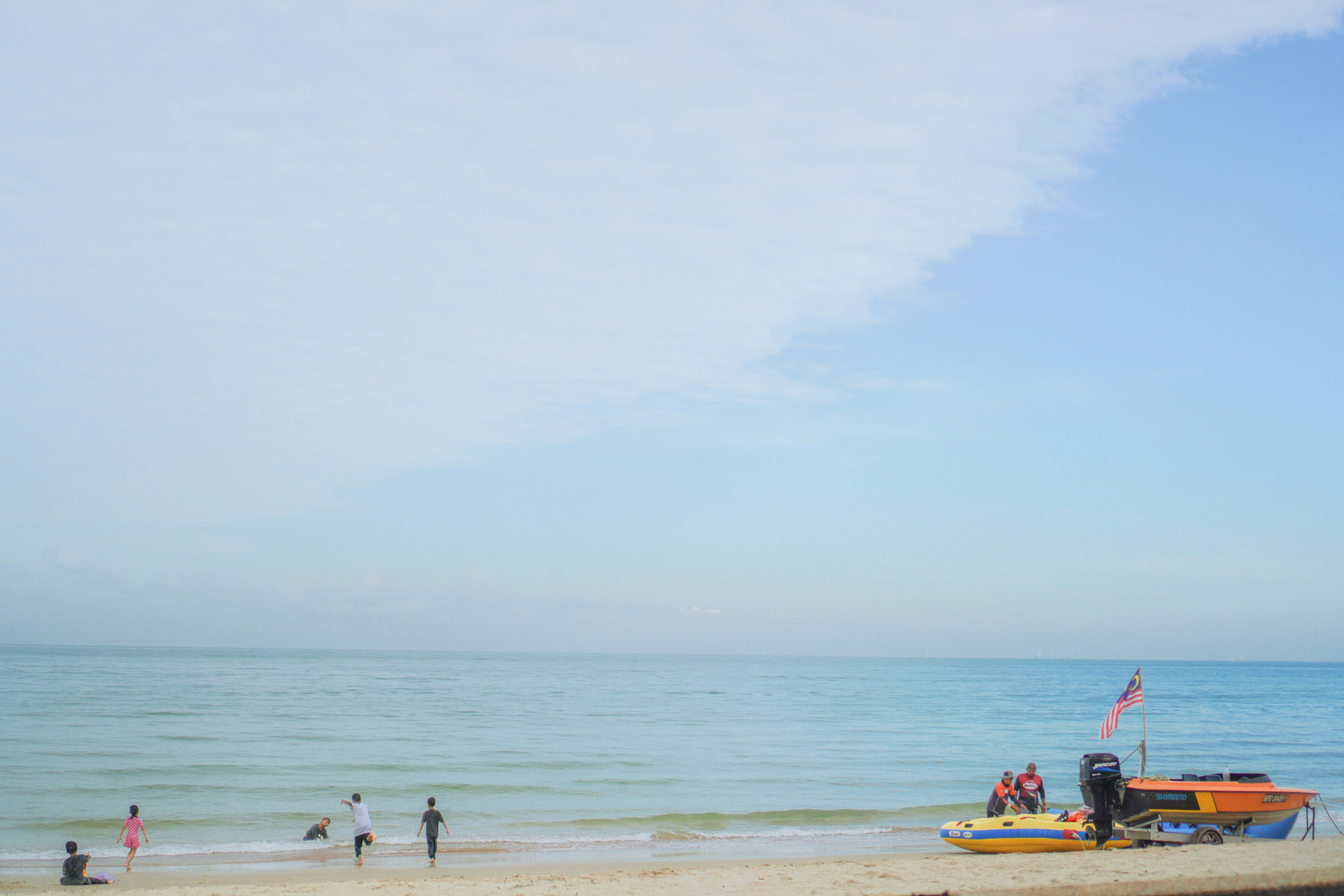 группа людей, стоящих на пляже у океана